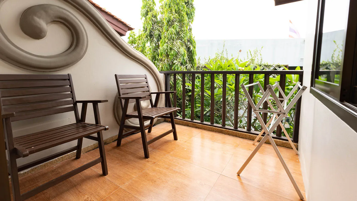 The Deluxe Room balcony features wooden chairs, a small table, a clothes drying rack, and scenic views of Kata and Kata Noi beaches