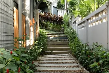 A hillside stone and gravel path with steps, surrounded by dense tropical greenery, likely part of the resort’s garden