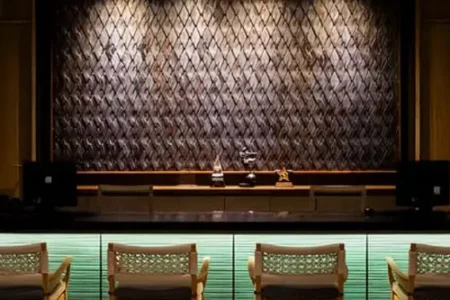 Elegant Phuket reception at Andaman Cannacia Resort with a sleek wooden front desk, woven seating, and a stylish textured wall backdrop