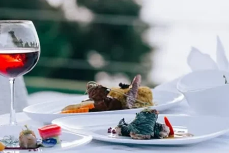 Set outdoors with scenic views of the Andaman Sea and Kata Beach, the table features several courses and a red wine glass